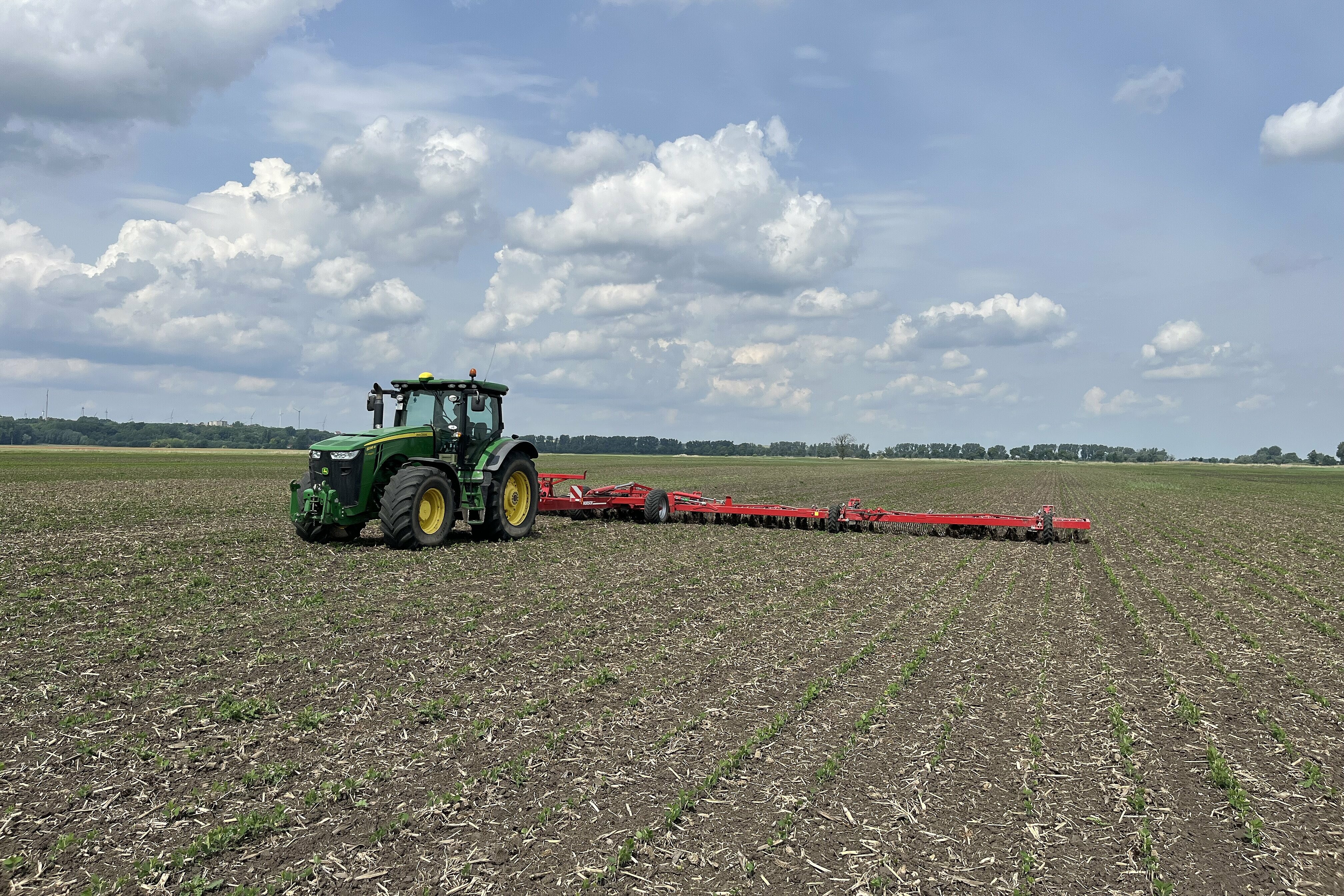 Traktor und Striegel auf dem Acker.