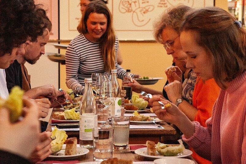 Viele Personen um einen Tisch herum, die essen.