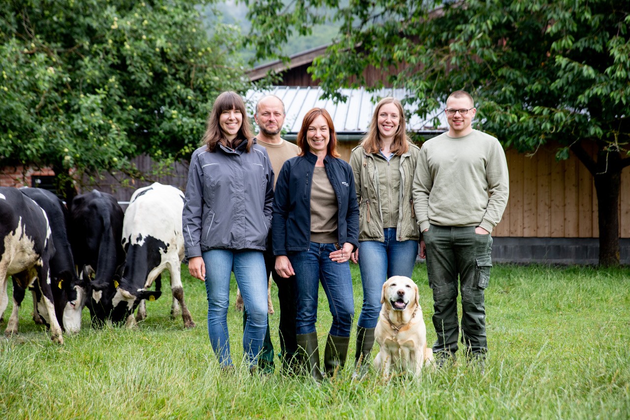 Gruppenfoto mit Hund, im Hintergrund Kühe.
